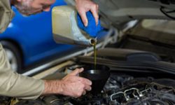 Mechanic pouring oil into car engine